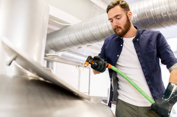 man with hose working at craft beer brewery kettle - Photo, image