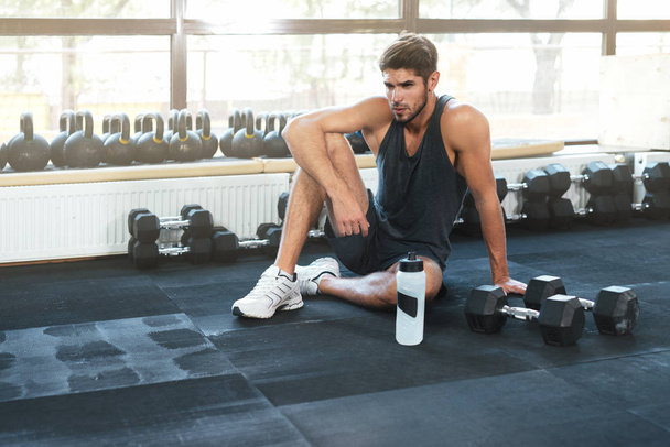 Fitness man sitting down in gym - Photo, image