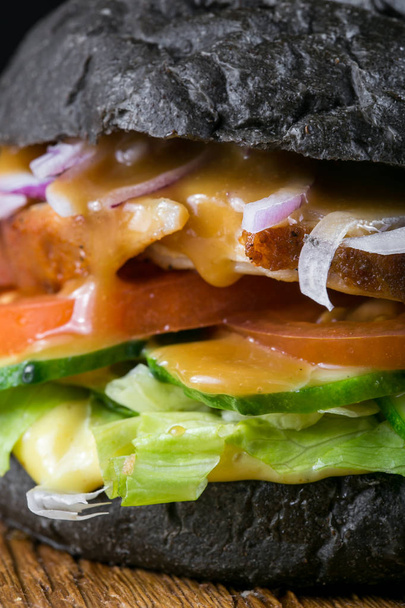 Fresh tasty burger on black background. Homemade Pork steak hamburger onion, tomato, lettuce and cheese with ingredients - Фото, изображение