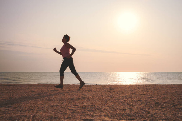 mulher sênior correndo na praia do mar
 - Foto, Imagem