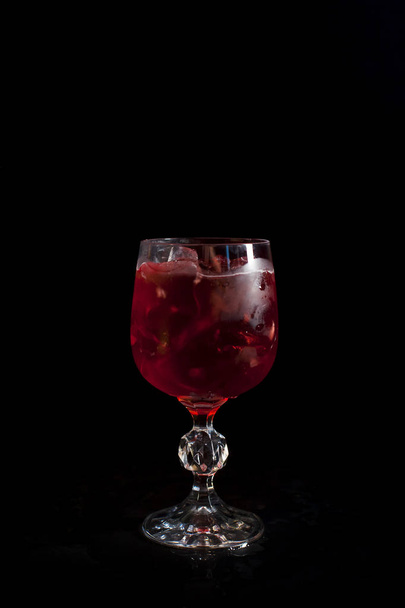 黒の背景に氷で赤い飲み物を持つガラス - 写真・画像