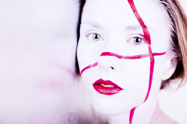Beauty portrait of girl with white face with red stripes and red lips  - Photo, Image