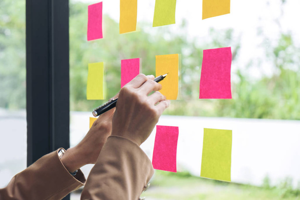 Young creative professional leader using post it notes in glass  - Фото, изображение