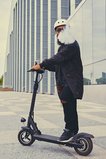 vapeo masculino y montar en scooter eléctrico
 - Foto, imagen