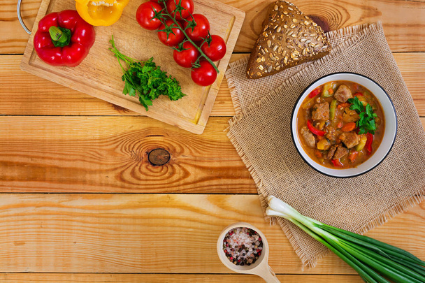 Guiso con carne y verduras en salsa de tomate sobre fondo de madera. Vista superior
 - Foto, imagen