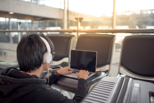 Giovane uomo asiatico utilizzando il computer portatile nel terminal dell'aeroporto
 - Foto, immagini