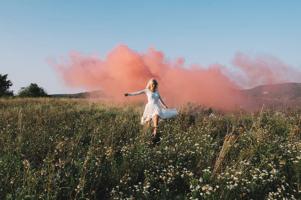 Lovely bride running outdoors, red smoke on background. Colourful wedding concept. - Fotoğraf, Görsel