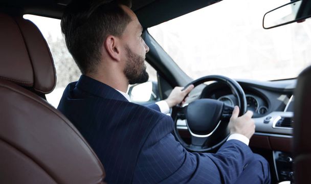 empresário senta-se ao volante em seu carro e olha para a estrada
 - Foto, Imagem