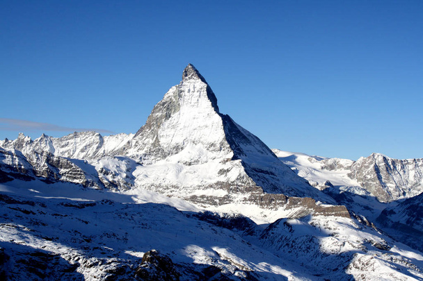 Festői kilátással a Matterhorn havas csúcs napsütéses napon a kék ég és néhány felhők, a háttérben - Fotó, kép