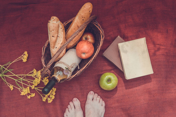 Piknik kosár, virágok, könyvek és női láb felső kilátás - Fotó, kép