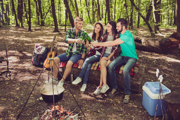 Four joyful friends are toasting at a campground in the wood in  - Fotografie, Obrázek