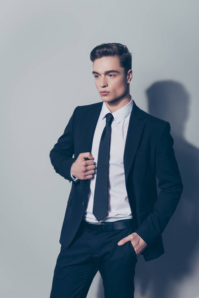 Vertical portrait of confident young guy in black suit touching  - 写真・画像