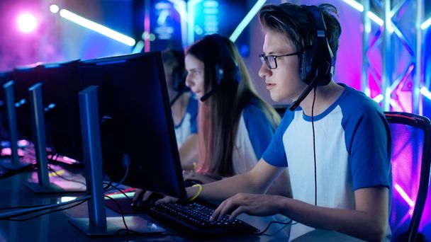 Team of Professional Cybersport Gamers Playing Video Games on a Cyber Games Tournament. Girls and Boys Have Headphones On, Arena is Lit with Neon Lights. - Zdjęcie, obraz