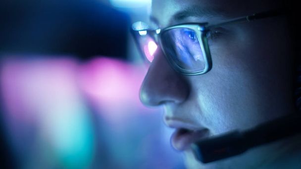 Close-up van tiener bril spelen van videogames in zijn hoofdtelefoon geven opdrachten in microfoon. - Foto, afbeelding