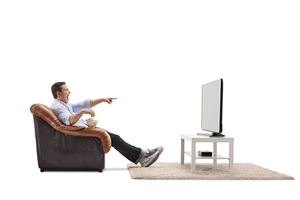 man in an armchair watching television and laughing - Фото, изображение