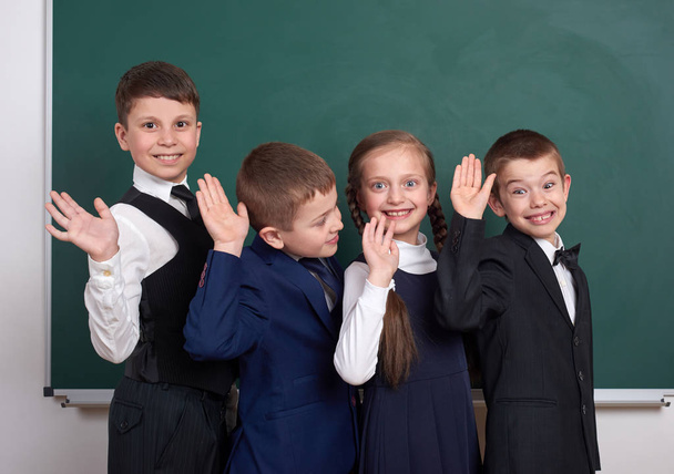 elementary school boy friends, fooling around near blank chalkboard background, dressed in classic black suit, group pupil, education and friendship concept - Photo, image