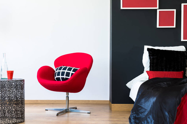 Multifunctional bedroom with red chair - 写真・画像
