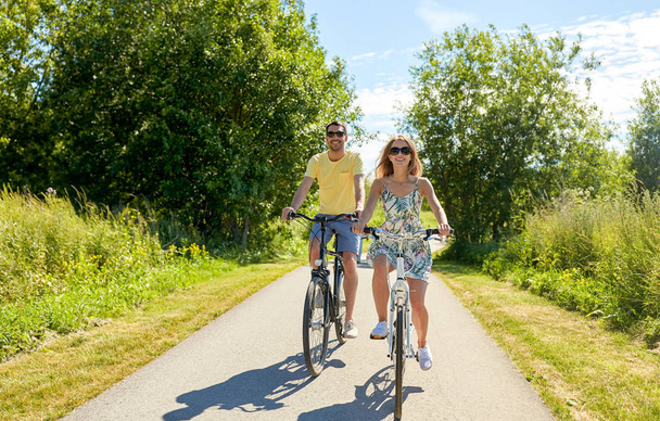 happy young couple riding bicycles in summer - Fotoğraf, Görsel