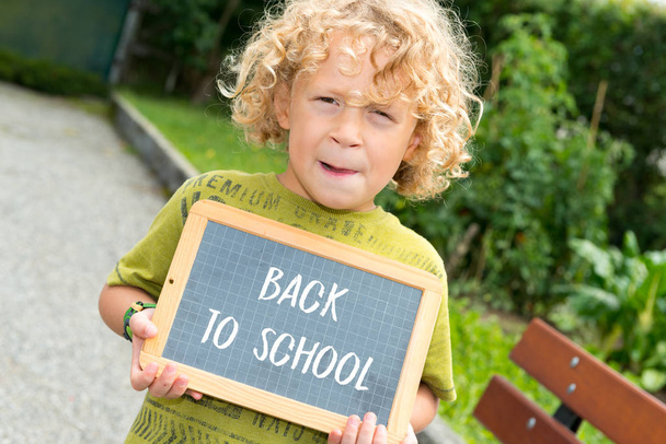  blond jongetje houden een schoolbord - Foto, afbeelding