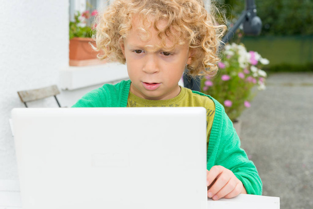 Retrato de un niño rubio usando un portátil
 - Foto, imagen