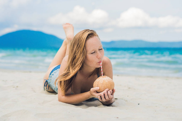 Fiatal nő iszik kókusztej, a strandon. - Fotó, kép