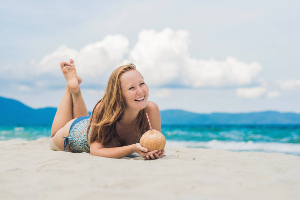 Young woman drinking coconut milk on beach. - Foto, Bild