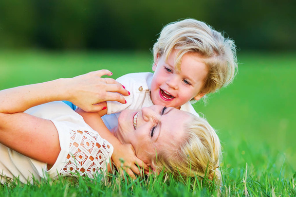 woman romps with her son on the grass - Foto, afbeelding