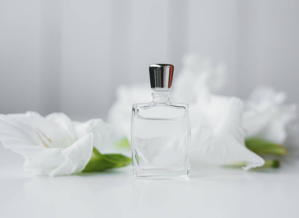 Piccola bottiglia di profumo con fiori sopra bianco
 - Foto, immagini