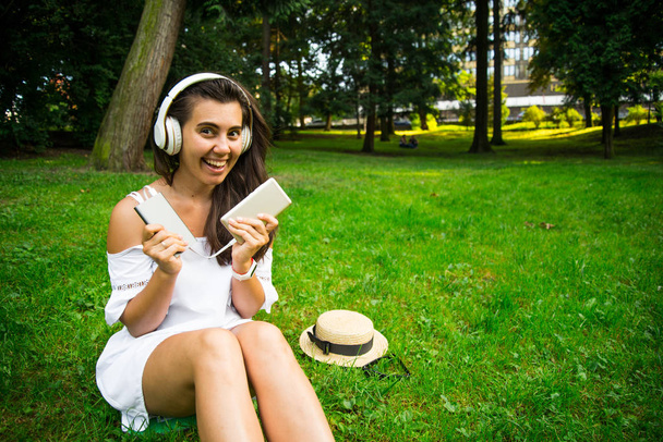 жінка в парку з радістю користується павербанком і продовжує слухати музику
 - Фото, зображення