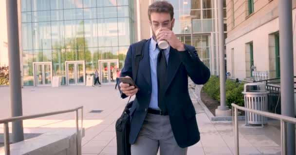 Frustrated executive millennial businessman walking and using smart phone in 4k - Felvétel, videó
