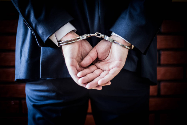 Бизнесмен с руками на спине и наручниками. Арестованный
 - Фото, изображение