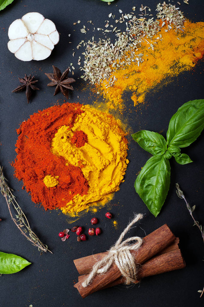 Paprika and turmeric in the form of a figure of "yin yang" on a dark surface. Spices, condiments, herbs on a dark surface - 写真・画像