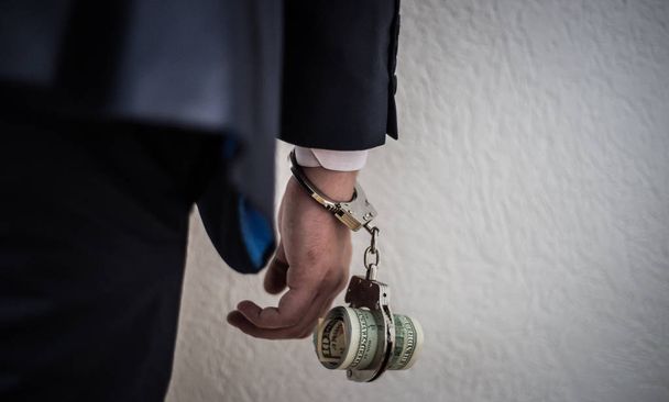 Een zakenman met handboeien gevangen op zijn buik voor corruptio - Foto, afbeelding