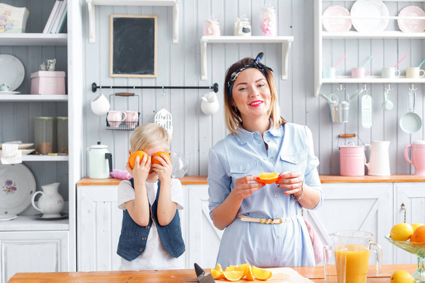 el niño cierra los ojos de color naranja. Engañando. hijo y madre joven en la cocina comiendo desayuno
. - Foto, imagen