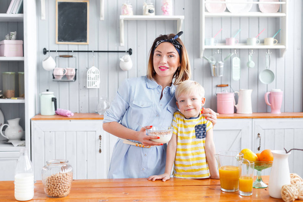 Mother and son are smiling while having a breakfast in kitchen. look at the camera - Photo, Image