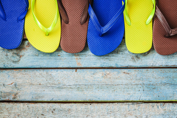 Several pairs of multi-colored rubber flip-flops exhibited in a  - Zdjęcie, obraz