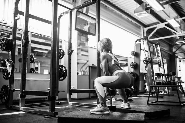 Young blonde sexy girl doing squat. - 写真・画像