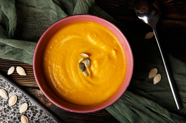 Pumpkin and carrot soup with cream on dark wooden background top view - 写真・画像