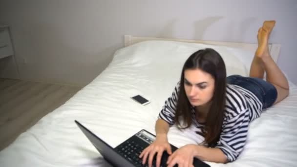 Freelancer girl is working at home lying on the bed - Filmagem, Vídeo