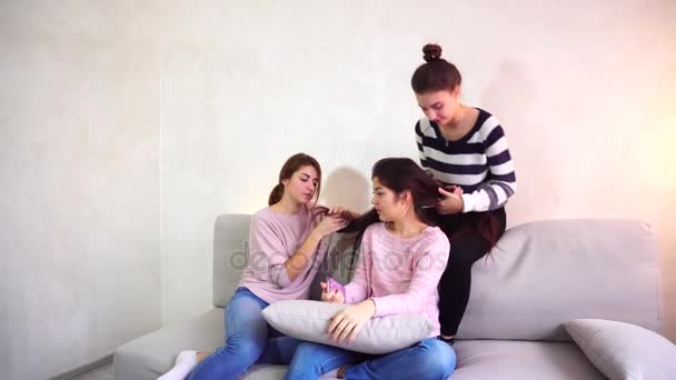 Cute girl friends collect girlfriend on date and help look beautiful, sit on couch in bright room in evening. - Footage, Video