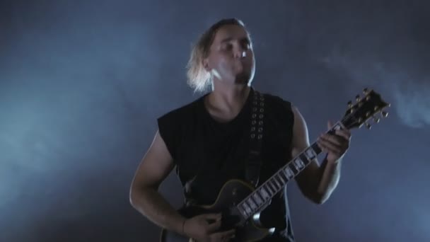 Brutalny mężczyzna rocker gra na gitarze elektrycznej. Film muzyka punk, heavy metal lub grupa rockowa. - Materiał filmowy, wideo