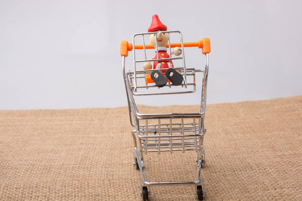 Pinocchio sitting on shopping trolley on a canvas background - Photo, Image