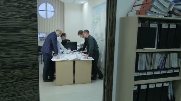 KAZAN, TATARSTAN/RUSSIA - DECEMBER 20 2016: Camera moves fast to people looking at data graphics on table in small room with map on wall on December 20 in Kazan - Filmagem, Vídeo