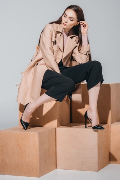 fashionable woman sitting on wooden blocks - 写真・画像