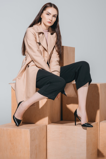 fashionable woman sitting on wooden blocks - Zdjęcie, obraz