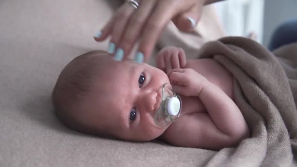 Newborn baby sucks pacifier in a bed, mother lulls the baby, the child falls asleep - Footage, Video