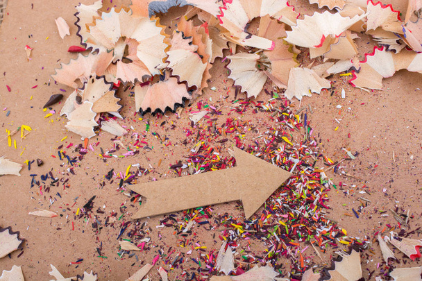 Arrow cut out of paper amid pencil shavings - Foto, afbeelding