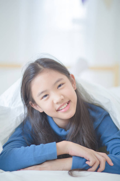 Szczęśliwa dziewczyna azjatyckich, leżąc na łóżku z promieni słonecznych na leniwy dzień - Zdjęcie, obraz