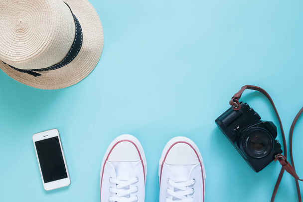 Blick auf das Selfie von Turnschuhen mit Smartphone, Kamera und Hut auf pastellfarbenem Boden - Foto, Bild