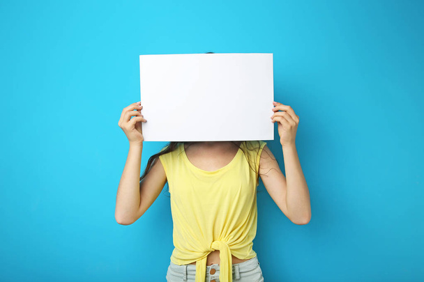 Young woman with blank paper on blue background - Foto, immagini